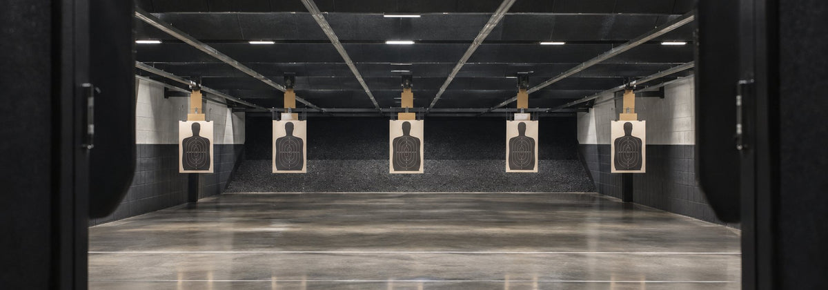 Paper silhouette qualification targets hanging on the carriers of an indoor shooting range