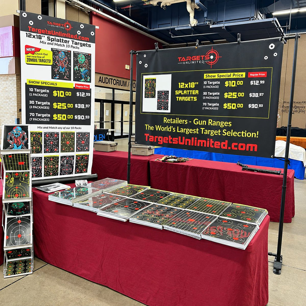 The Targets Unlimited booth at a gun show: a table of splatter target packs under a 12x18 splatter targets banner
