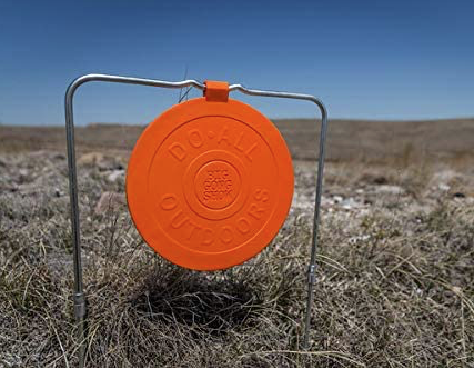 Do-All Outdoors 9" orange self-healing gong on its wire stand in a dry field